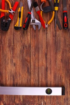 This is an overhead photo of construction tools and brush with copy space on a wood background. There is a lot of space