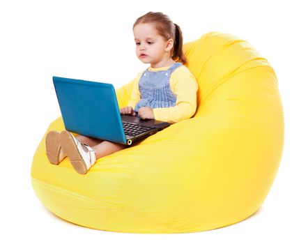 Portrait of a child sitting on a bean bag with laptop. Isolated on white.