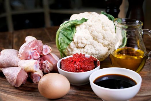 Ingredients for Cooking. Recipe. Baked chicken drumsticks with cauliflower served on a wooden table. Rustic style. Top view