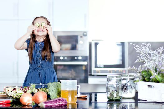 little daughter cooking in the kitchen at home. Girl Assisting In Preparing Food - Stock image