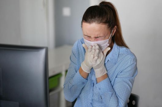 Ill young woman using laptop wearing face mask and coughing, sneeze, working from home or at office