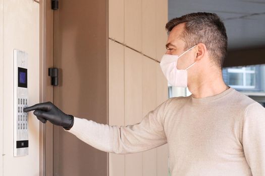 Caucasian man going home after shopping and carrying packet. Male in medical mask masked dials the door code