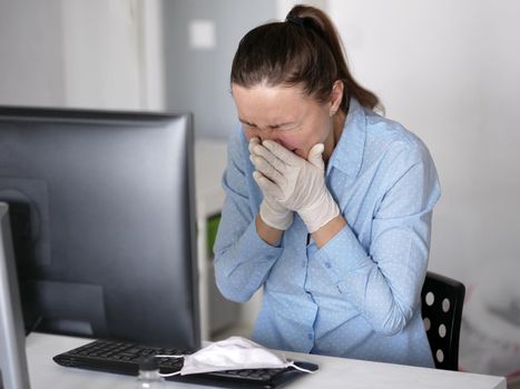 Ill young woman using laptop wearing face mask and coughing, sneeze, working from home or at office