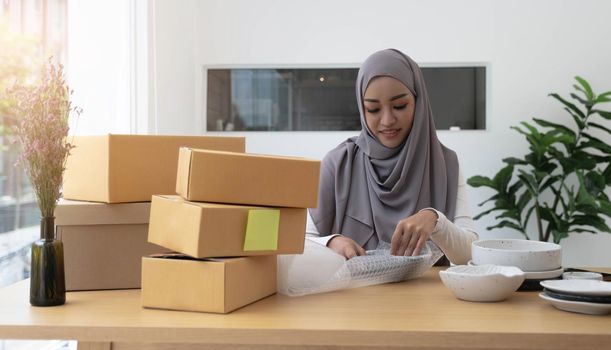 Muslim Business owner woman working online shopping prepare product packaging process at the office, young entrepreneur concept..
