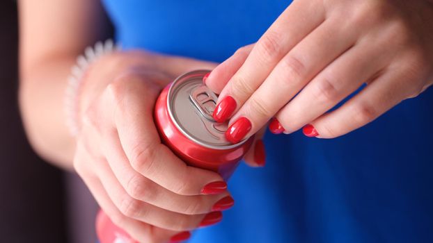 Woman with red manicure opening iron can with drink closeup. Soft carbonated drinks concept