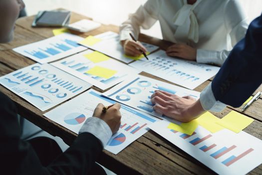 Male businessman pointing to take summarizing marketing strategy documents with female colleagues in meeting, teamwork, investment planning.