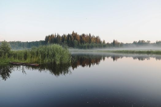summer evening twilight view on picturesque plain lake surface with reflections of sky and trees.
