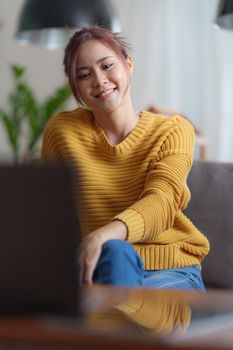 Portrait of happy asian beautiful girl making video calling with laptop and waving on phone screen at home. job interview remotely concept