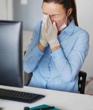 Ill young woman using laptop wearing face mask and coughing, sneeze, working from home or at office