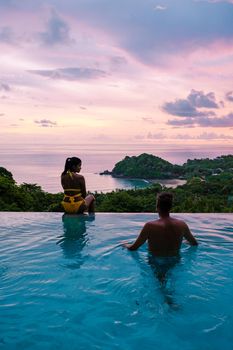 a young couple of men and women at a swimming pool during a vacation on a tropical island. man and woman in infinity pool during sunset. luxury vacation in Thailand pool of a luxury pool villa