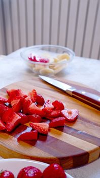 Sliced strawberry on wooden board. Preparing smoothie or milkshake with strawberry and banana.