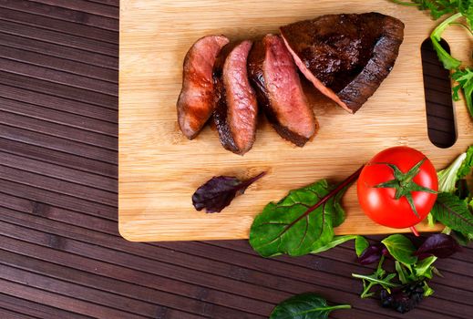 Close-up of Medium Rare Roast Beef with Fresh Herbs and Vegetables