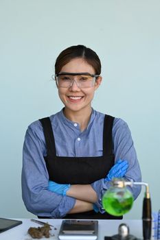 Female researcher sitting in scientific laboratories and smiling at camera. Herbal alternative medicine, cbd oil concept.