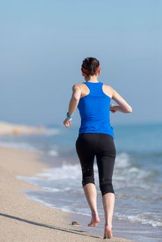 young woman runs on a seashore sandy beach in the morning