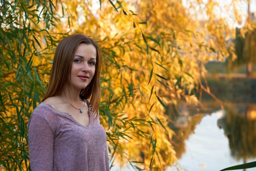 Autumn is one of the four temperate seasons. Outside the tropics, autumn marks the transition from summer to winter. Portrait of a cute young woman with brown fair hair and golden autumn leaves
