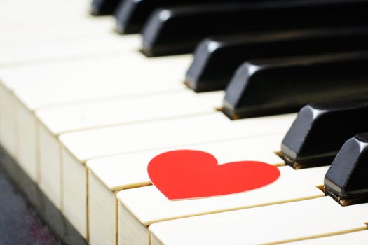 Red heart on a keys of a keyboard of an classic old piano