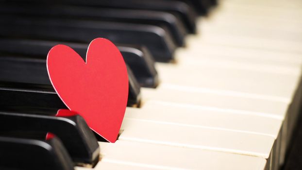 Small red paper heart on piano keys
