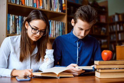 Students looking through books, looking for information, helping each other in studying