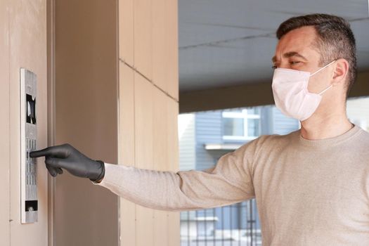 Caucasian man going home after shopping and carrying packet. Male in medical mask masked dials the door code