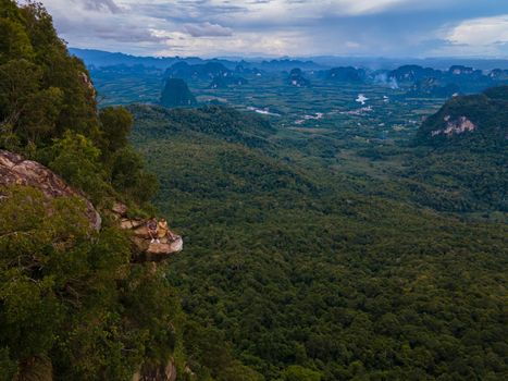 Dragon Crest mountain Krabi Thailand, a Young traveler sits on a rock that overhangs the abyss, with a beautiful landscape. Dragon Crest or Khuan Sai at Khao Ngon Nak Nature Trail in Krabi, Thailand