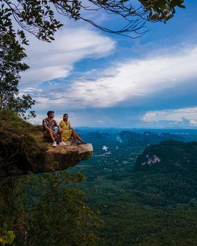 Dragon Crest mountain Krabi Thailand, a Young traveler sits on a rock that overhangs the abyss, with a beautiful landscape. Dragon Crest or Khuan Sai at Khao Ngon Nak Nature Trail in Krabi, Thailand