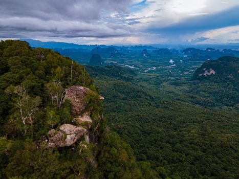 Dragon Crest mountain Krabi Thailand, a Young traveler sits on a rock that overhangs the abyss, with a beautiful landscape. Dragon Crest or Khuan Sai at Khao Ngon Nak Nature Trail in Krabi, Thailand