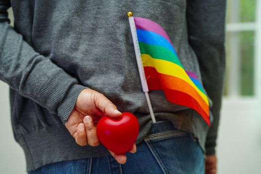 Asian woman holding red hert with rainbow flag, LGBT symbol rights and gender equality, LGBT Pride Month in June.