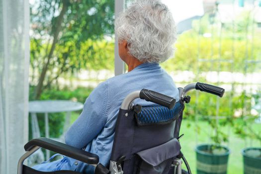 Asian elderly woman disability patient sitting on electric wheelchair in park, medical concept.