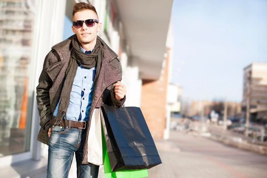 Young sexy man with bags doing shopping at the city center