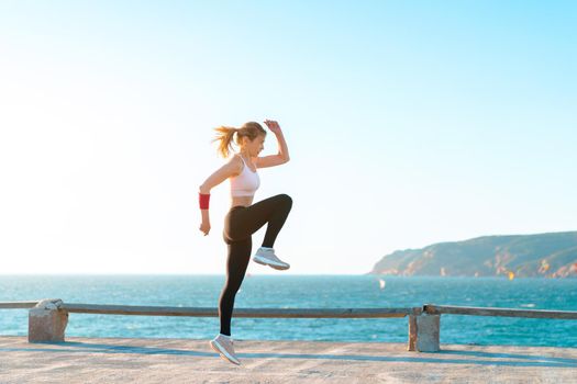 Young fit woman jumping high on beach with sunset, active caucasian young adult female workout with , bodyweight training exercise for woman, self motivation. Caucasian female jump training