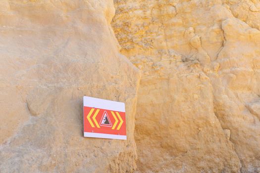 sign with warning of danger of collapsing cliffs on the beach