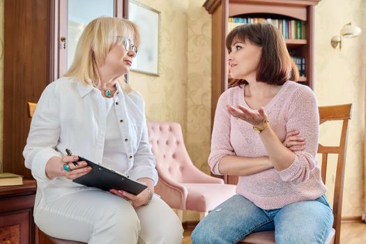 Mature female psychologist counseling a middle aged woman. Smiling, talking doctor and patient in the office. Mental health of age people, psychology, support, help, psychotherapy concept