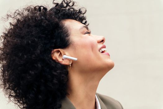 portrait of a happy woman with wireless earphones laughing and enjoying listening to music, concept of youth and technology, copy space for text