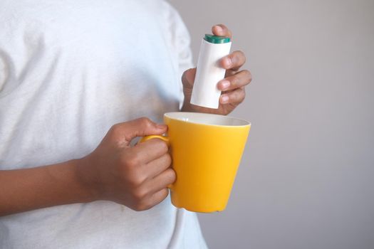 young man putting artificial sweetener in tea