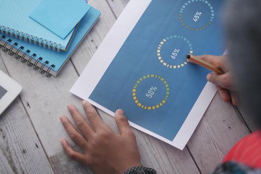 man hand with pen analyzing bar chart on paper.