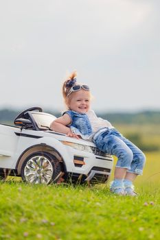 little girl standing near her baby car