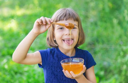 Child a plate of honey in the hands. Selective focus.