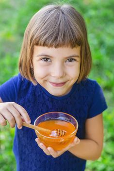 Child a plate of honey in the hands. Selective focus.