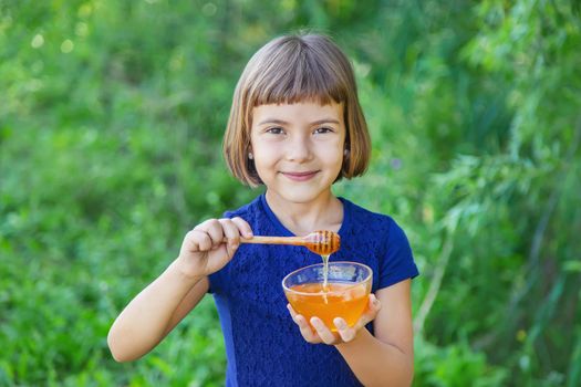 Child a plate of honey in the hands. Selective focus.