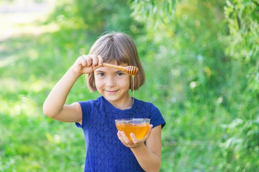 Child a plate of honey in the hands. Selective focus.