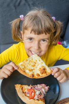 The child eats cheese pizza. Selective focus.