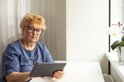 telemedicine concept, old woman with tablet pc during an online consultation with her doctor in her living room.