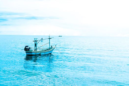 Small fishing boat floating in blue sea with blue sky Thailand.