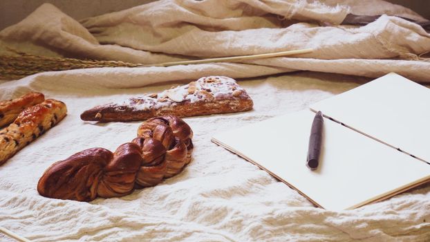 Breads and toast for breakfast and note book on white bed sheet background, Healthy breakfast. Morning health lifestyle concept idea background