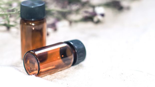 Bottle of essential oil. Herbal medicine or aromatherapy dropper bottle isolated on white background. Fresh rosemary flowers and essential oils on the table