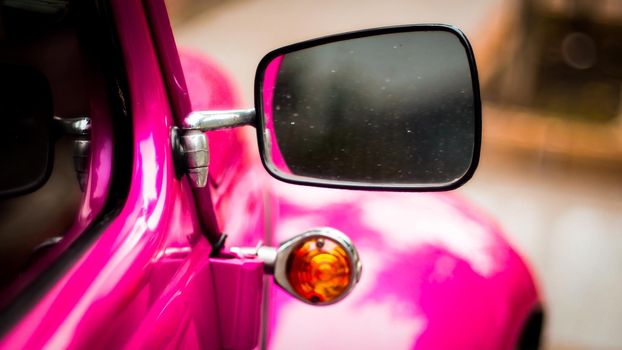 Side mirror and window of apink vintage car