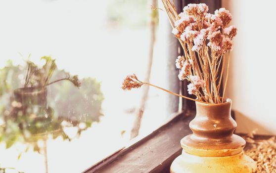 A small plant pot displayed in the window. Bouquet of flowers near window with curtain . lifestyle for living home idea