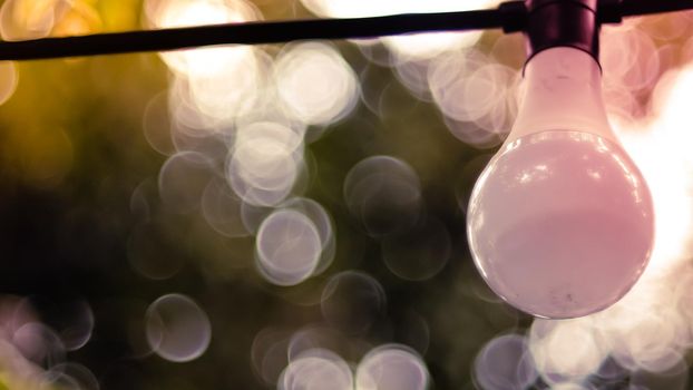 Beautiful retro bulb light lamp decor. Hanging decorative Christmas lights for an outdoor party. Blur bokeh background