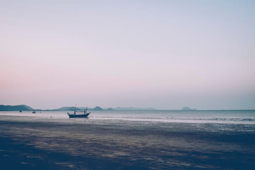 Silhouette people walking on the beach in sunset view.  Beach and mountains overlooking the ocean . boat in the sea