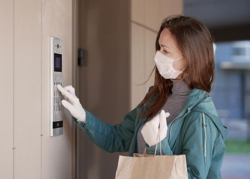 Courier's hands in latex white medical gloves deliver parcels in brown cardboard boxes to the door during the epidemic of coronovirus,COVID-19.Safe delivery of online orders during the epidemic.